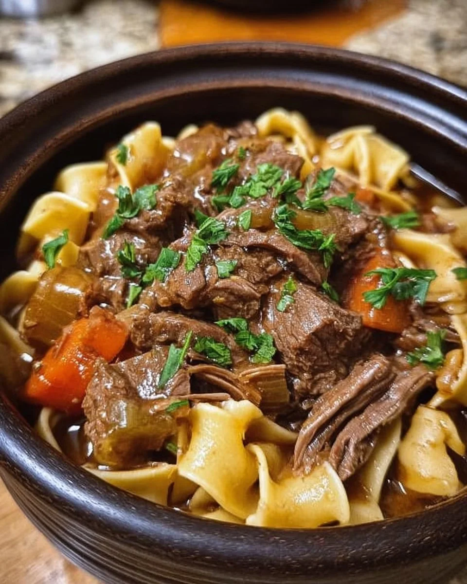 Delicious slow-cooked beef and noodles served in a bowl with herbs