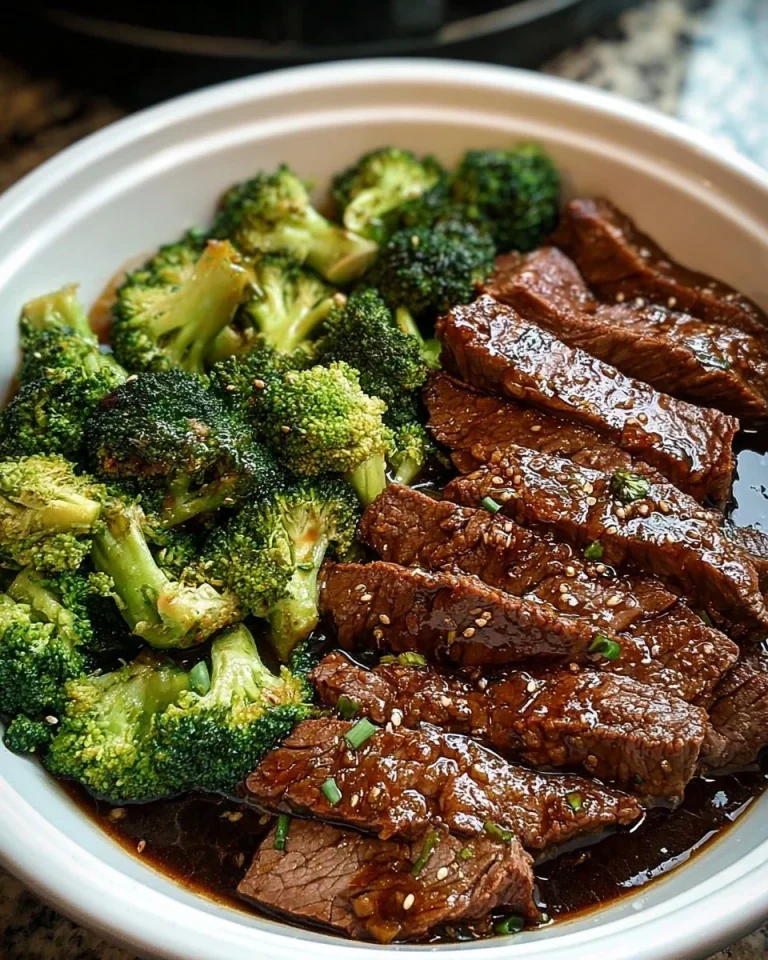 Slow cooker beef and broccoli dish garnished with sesame seeds and served over rice