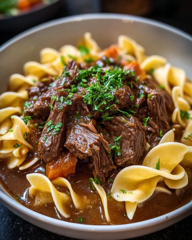 Slow Cooker Beef and Noodles dish served in a bowl with herbs on top.