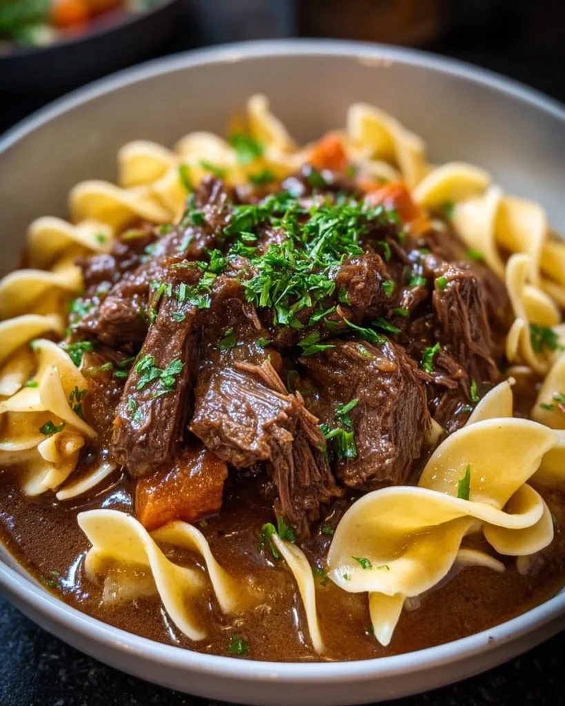 Slow Cooker Beef and Noodles dish served in a bowl with herbs on top.